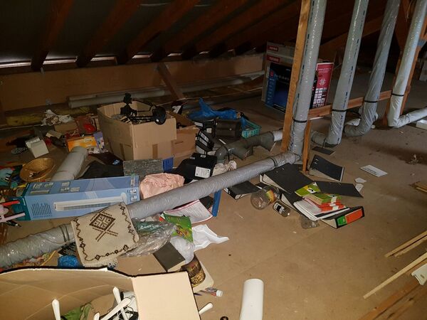 Chaotischer Dachboden mit Kartons, Ordnern, Rohren und verschiedenen Haushaltsgegenständen.