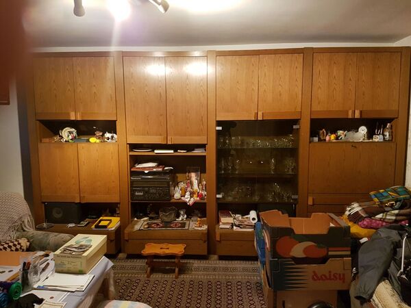 Große Wohnwand aus Holz mit Glastüren, Dekoration, Hifi-Anlage und Umzugskartons im Wohnzimmer.